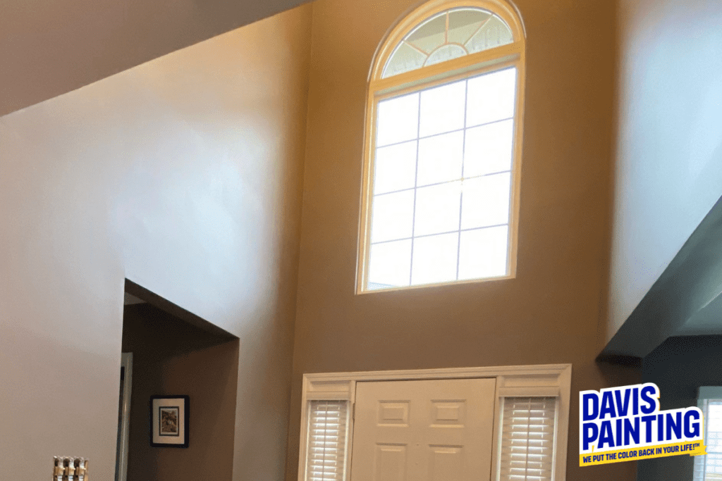 A tall, freshly painted gray wall with an arched window above a white door. Below, a logo for Davis Painting is displayed, reading "We put the color back in your life!.